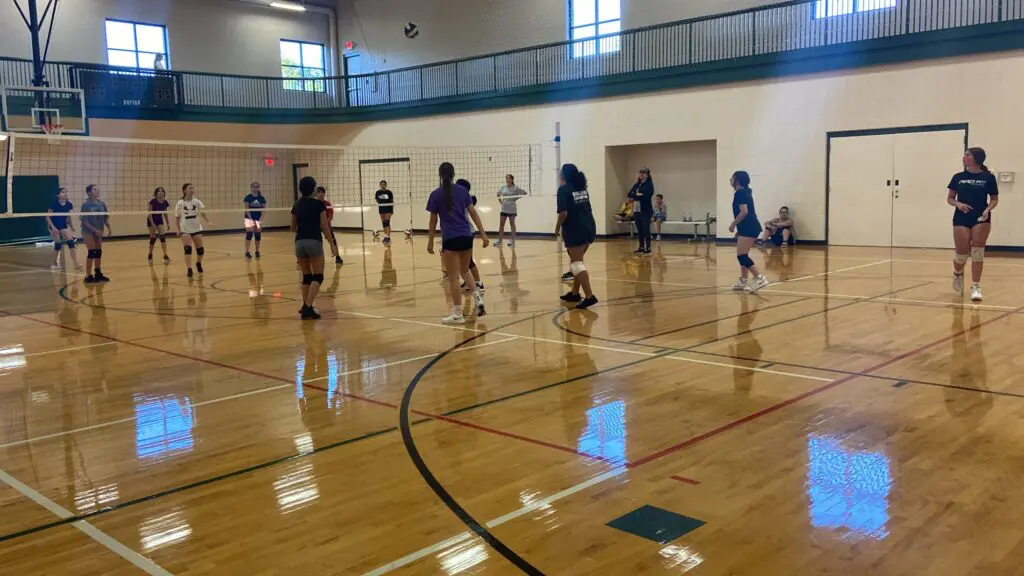 a group of people playing volleyball in a gym