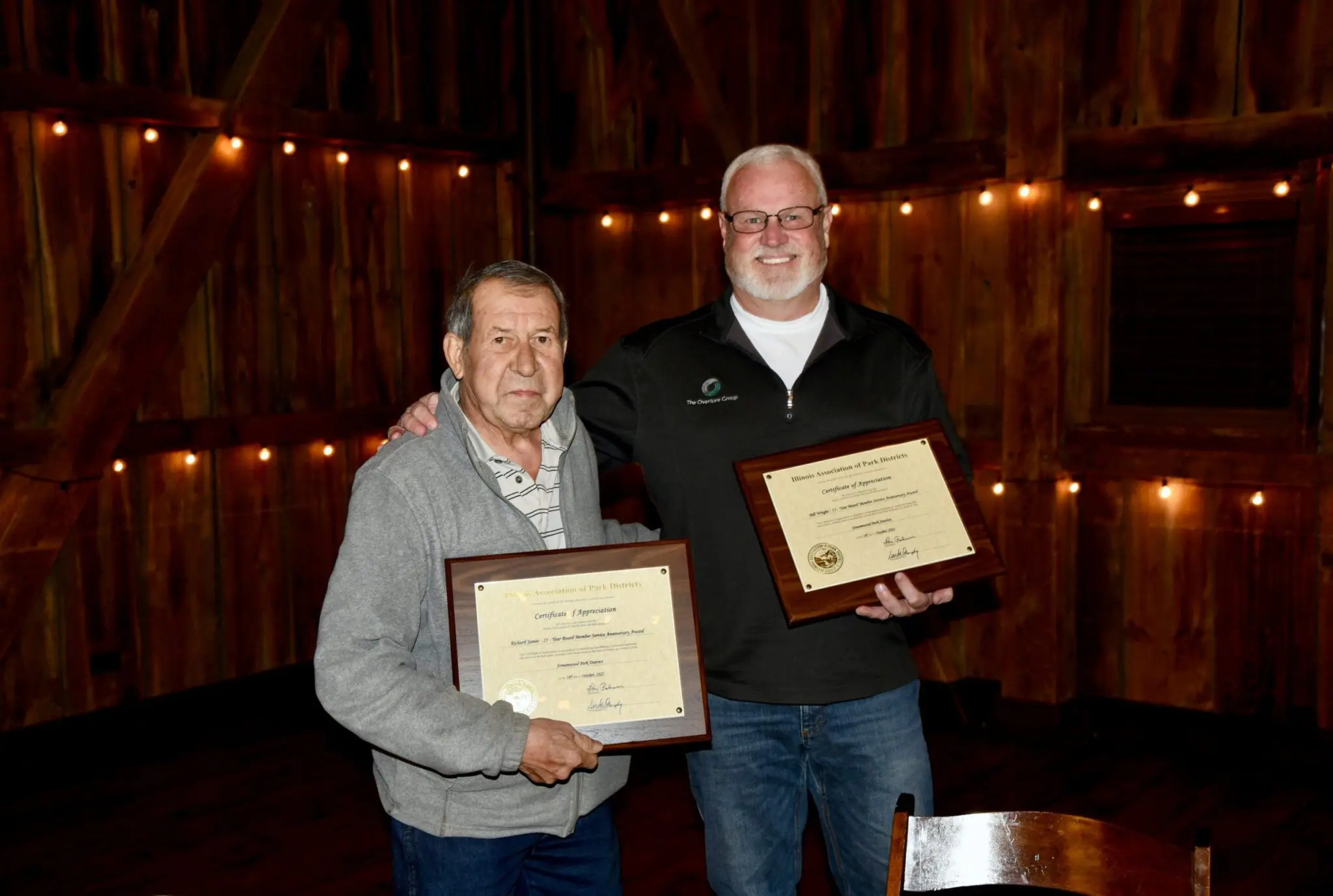 two men holding certificates in a room
