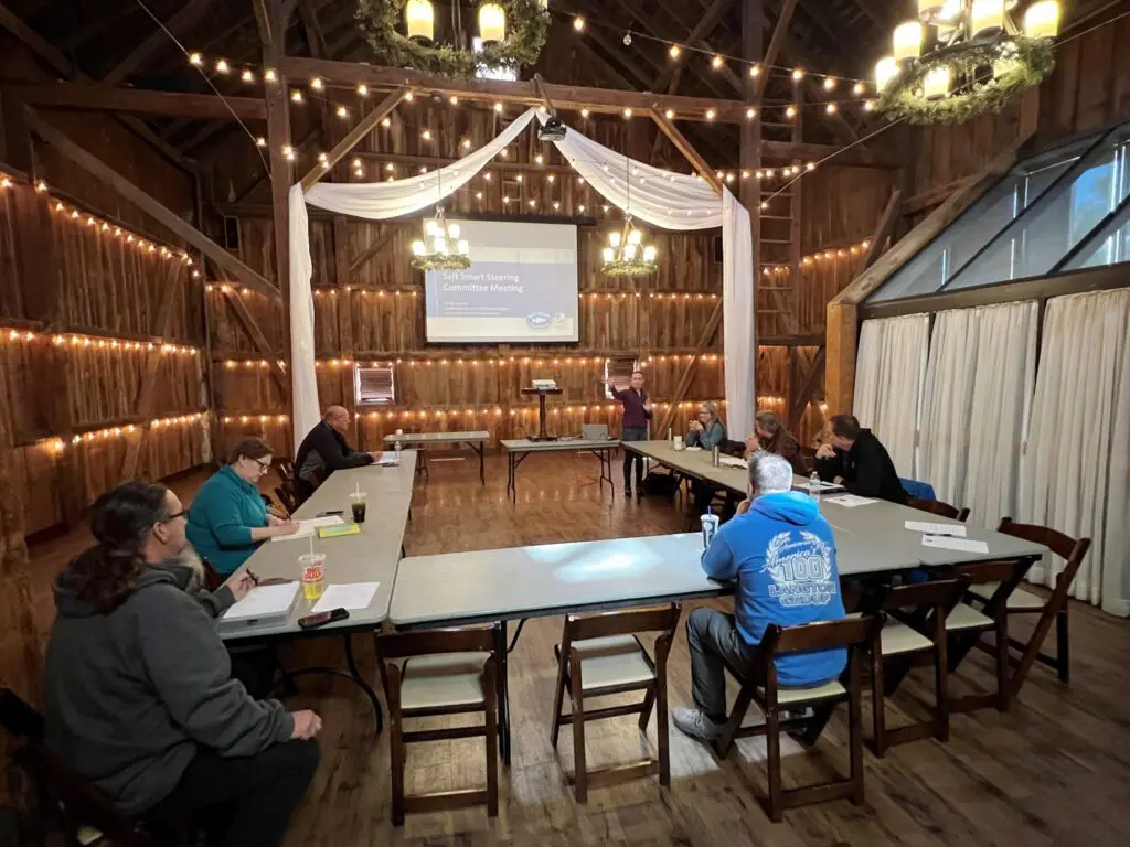 a group of people sitting around tables in a barn