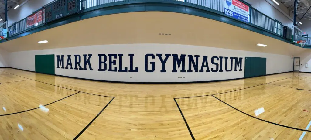 a gym with a wood floor and a sign