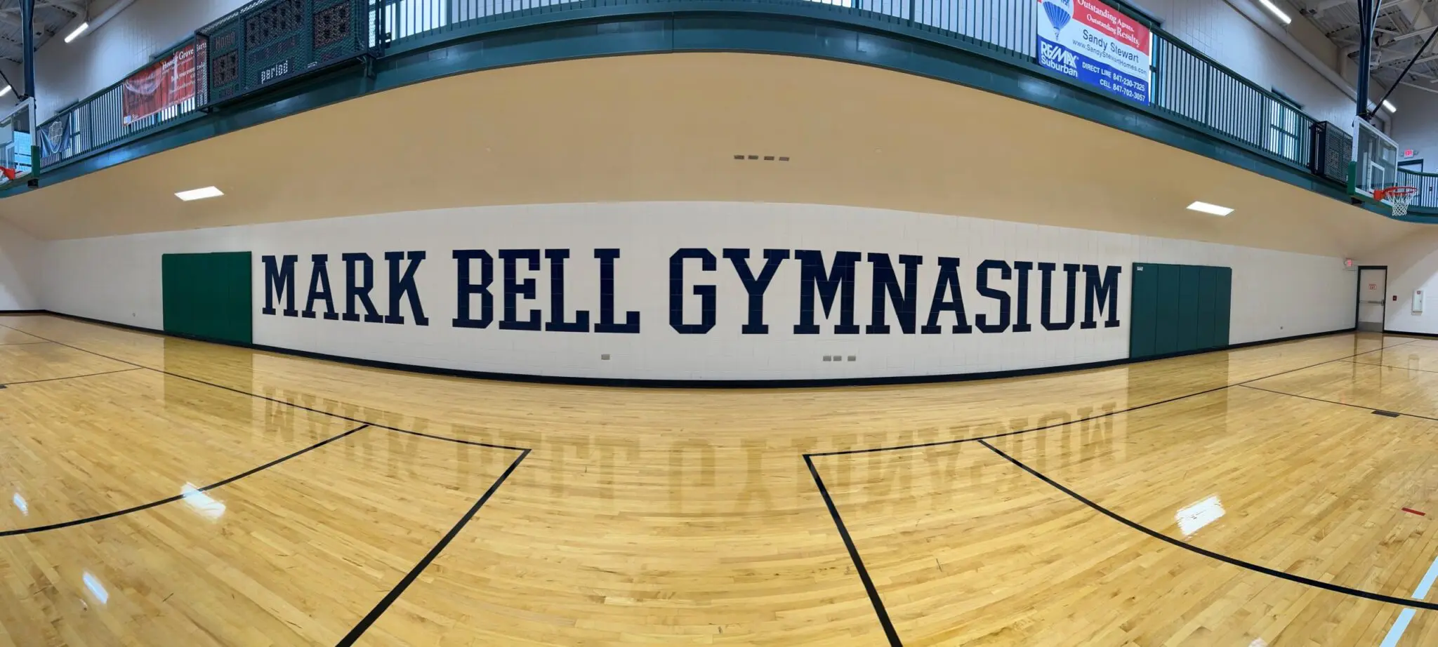 a gym with a wood floor and a sign