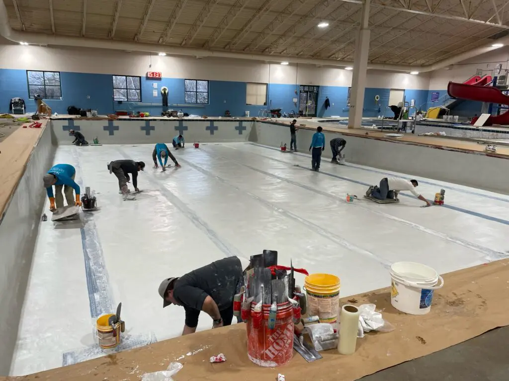 a group of people working on a large indoor pool