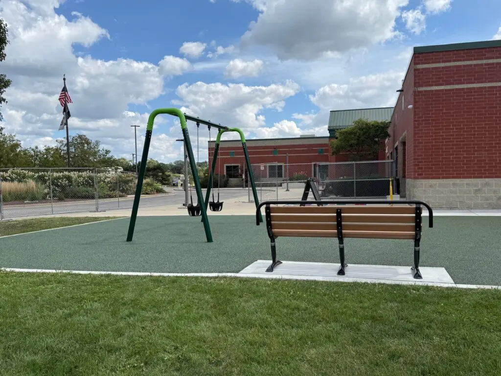 a playground with swings and a bench