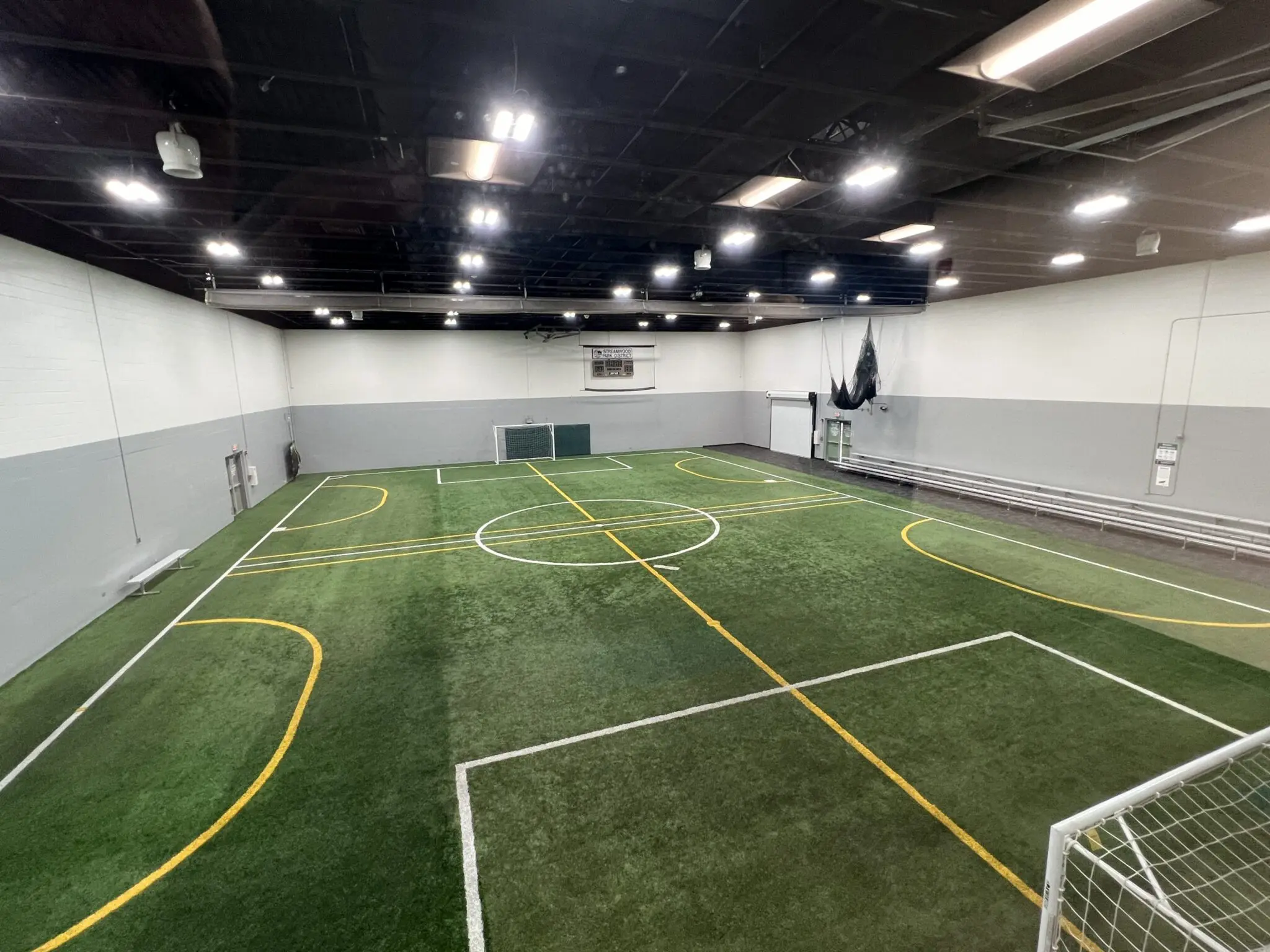 a indoor football field with white lines and yellow markings
