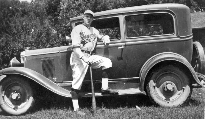 a baseball player leaning on a car