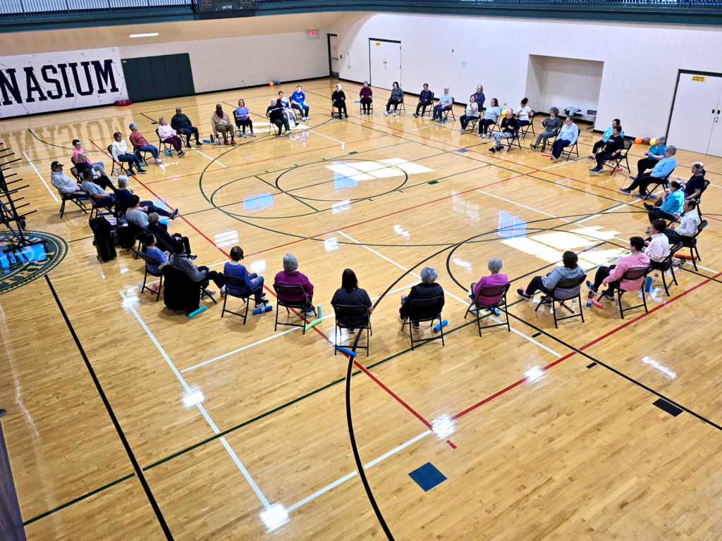 a group of people sitting in chairs in a gym
