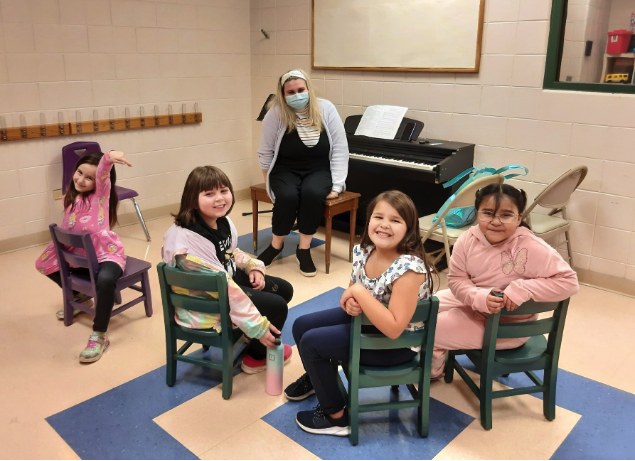 a group of children sitting in chairs in a room with a person