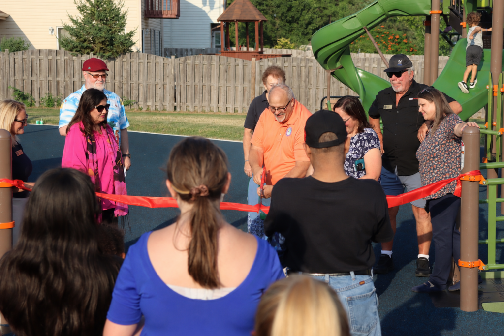 a group of people cutting a red ribbon