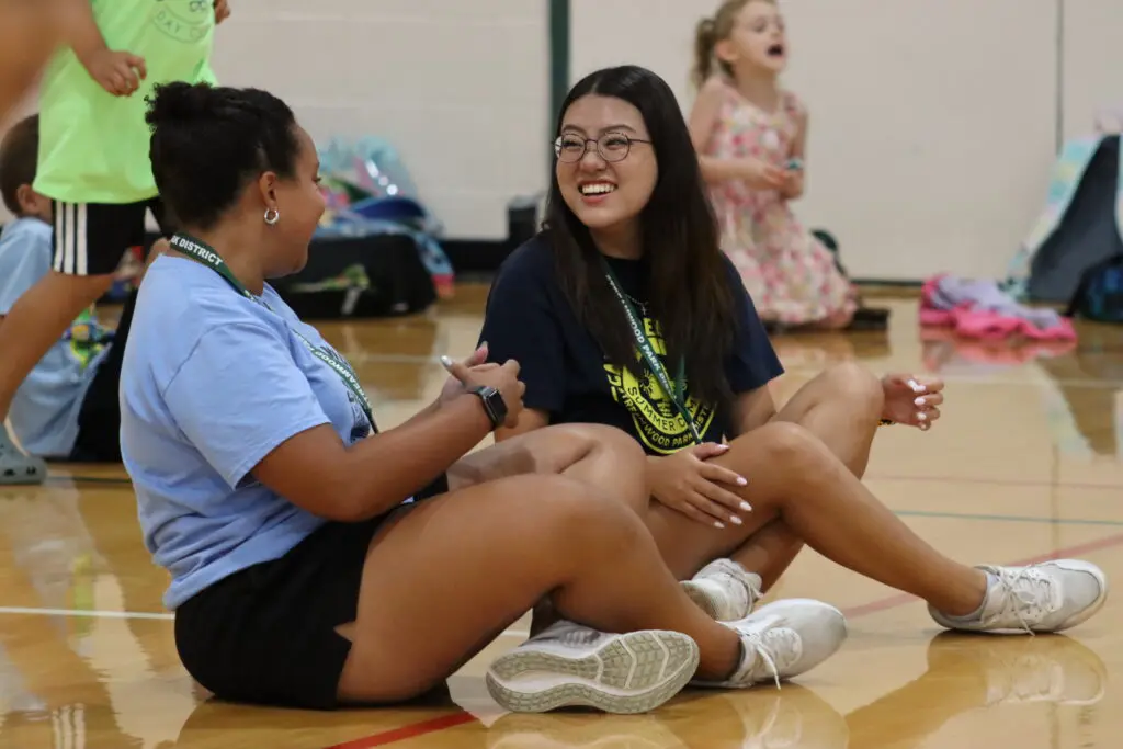 2 girls sitting on a gym floor