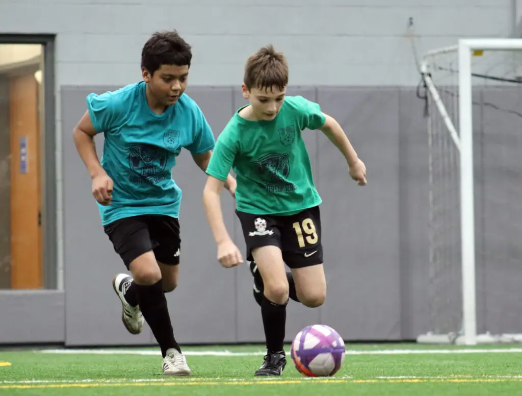 2 boys going after a soccer ball