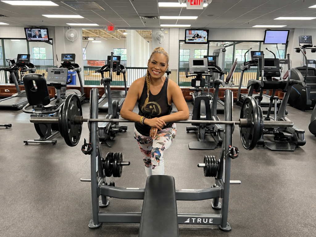 personal trainer posing behind a bench press machine