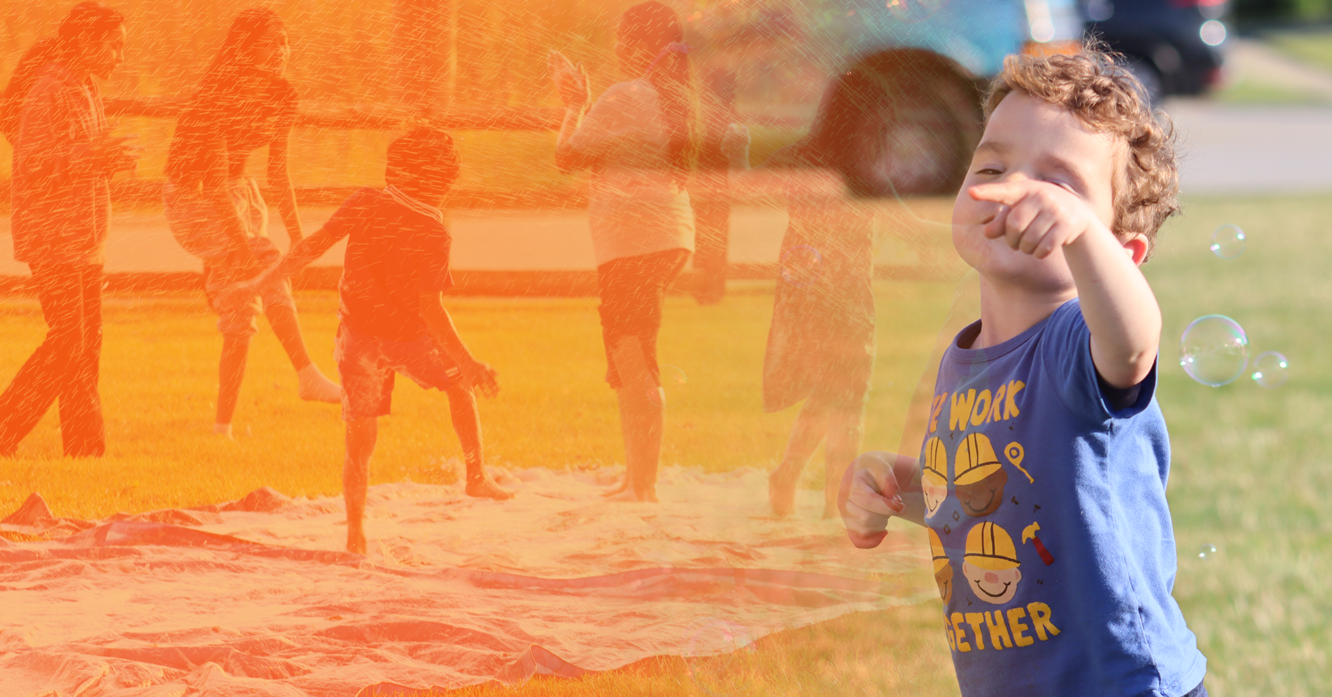 curly-haired, red-headed child pointing while staring into the sky with his eyes closed.